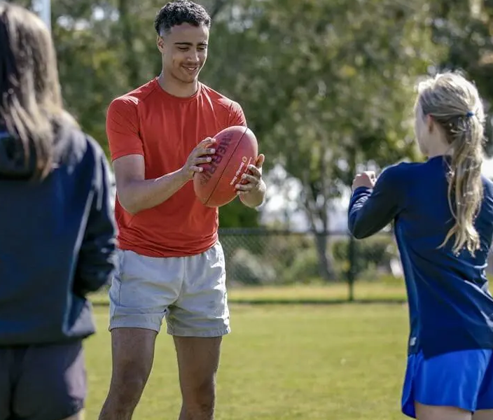 Man playing with rugby football with two young female kids